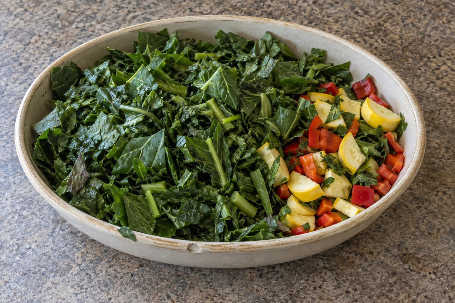 Shallow ceramic dish filled mostly with chopped collard, dandelion and turnip greens, with a smaller portion of chopped yellow squash and red bell pepper