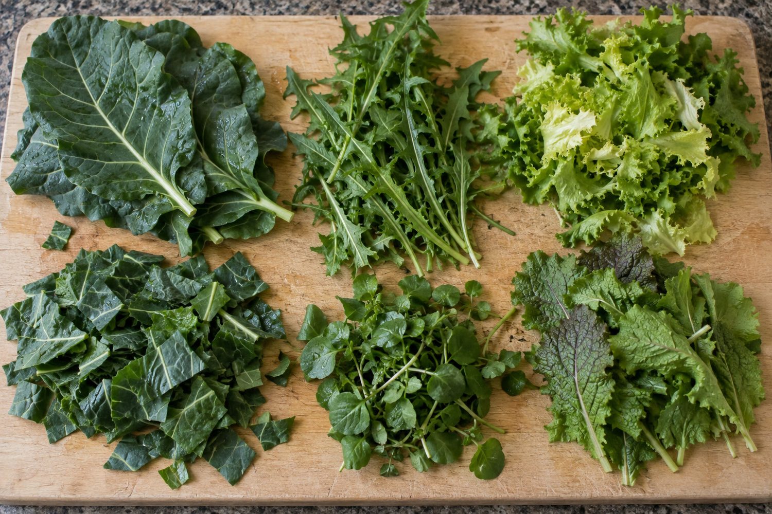 Collard greens, dandelion greens, escarole, watercress and mustard greens, some whole and some chopped, on a cutting board seen from above