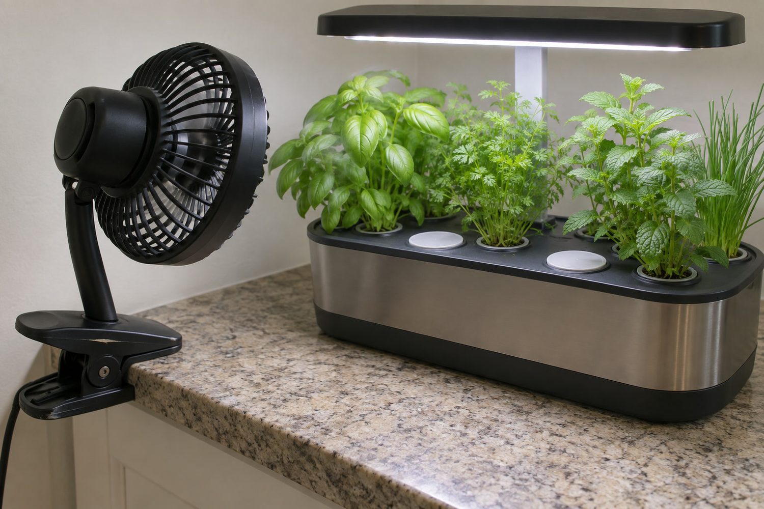 Small clip-on fan clamped to a counter edge aimed across the herbs of a countertop hydroponic garden, with plain covers capping two unused pod holes
