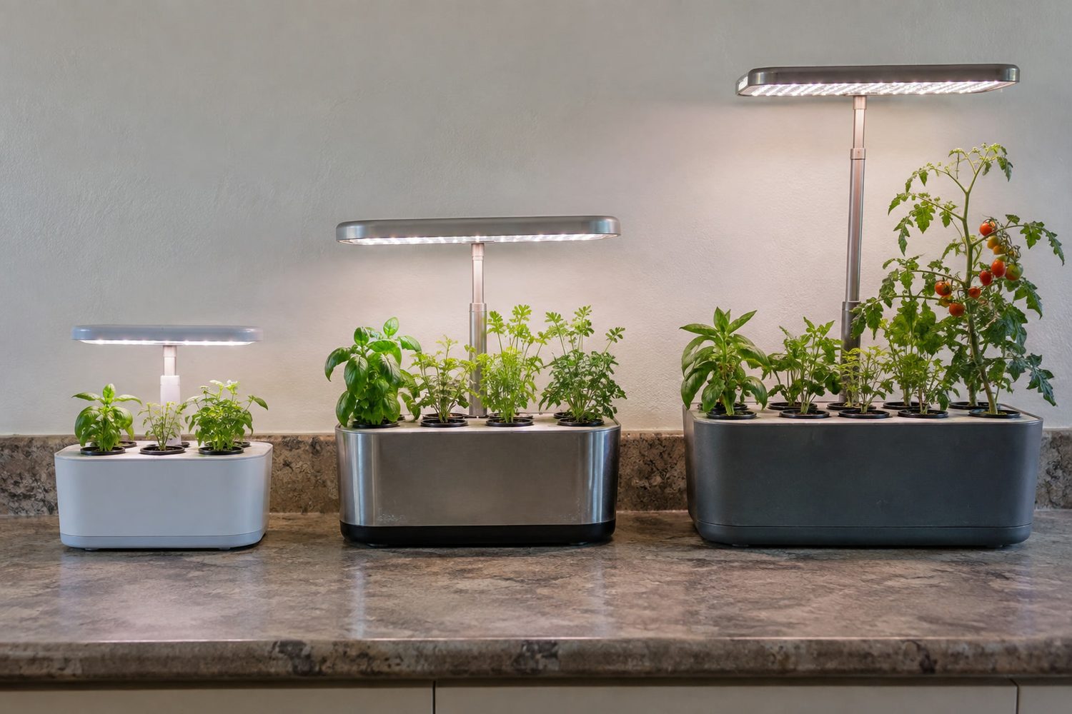 Three countertop hydroponic gardens side by side in increasing size, a small three-pod unit, a six-pod unit with herbs, and a tall nine-pod unit with its lamp raised high over a small tomato plant