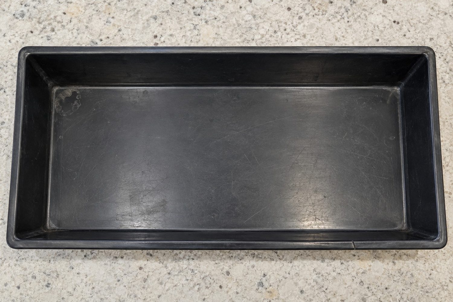 Empty shallow black 10 by 20 inch growing tray seen from above, its sloped walls and rounded inside corners making the flat floor smaller than the rim